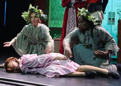 Two students perform lines to the audience as another lies ‘asleep’ on the floor in front of them in the Priestnall School Frozen Jr Production.