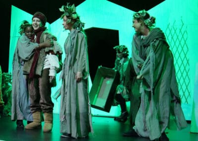 Two students hug and others move around the stage in the Priestnall School Frozen Jr Production.